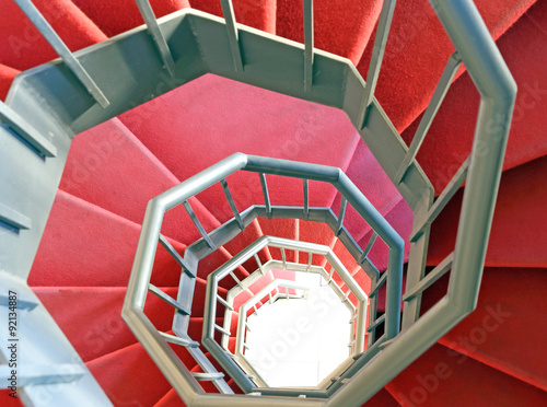 long wrought iron spiral staircase with red carpet