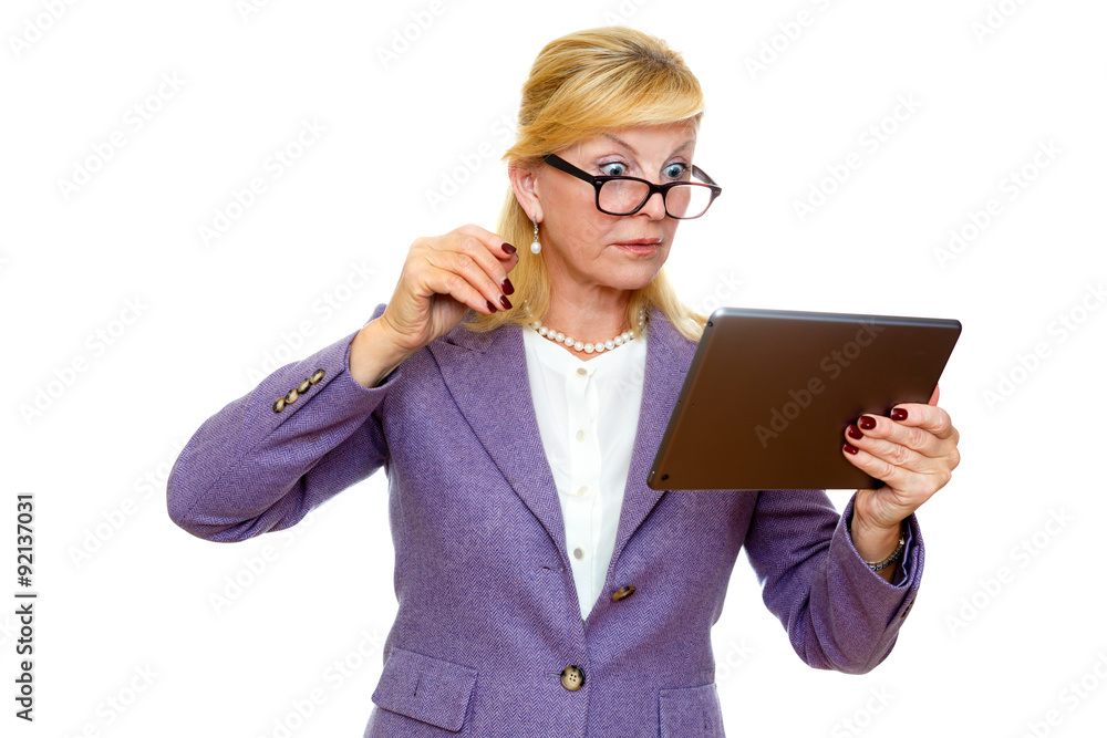 Surprised old senior business woman 60-65 years in glasses and suit, using digital tablet pc computer reading ebook. Isolated on white background Surprised old senior business woman 60-65 years in glasses and suit, using digital tablet pc computer reading ebook. Isolated on white background