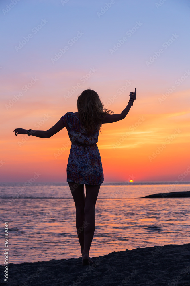 Beautiful young woman on the sea beach at sunset