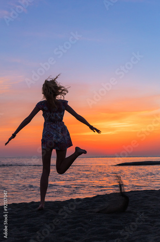 Beautiful young woman on the sea beach at sunset