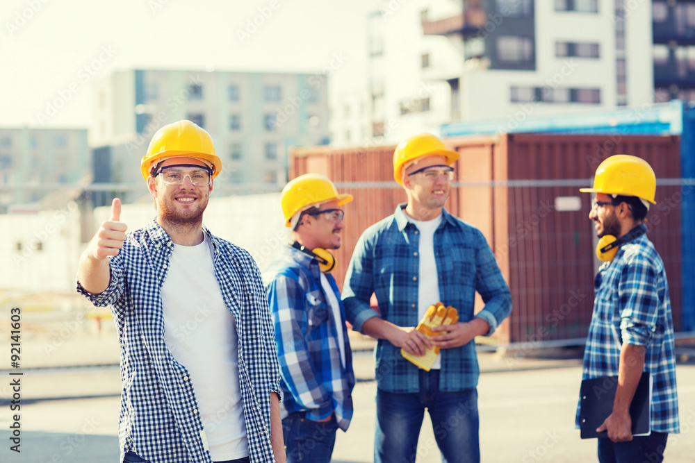 group of smiling builders in hardhats outdoors group of smiling builders in hardhats outdoors