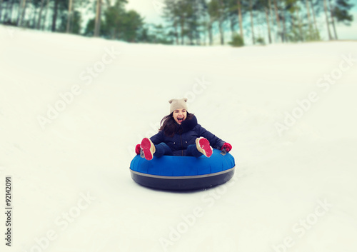 happy teenage girl sliding down on snow tube