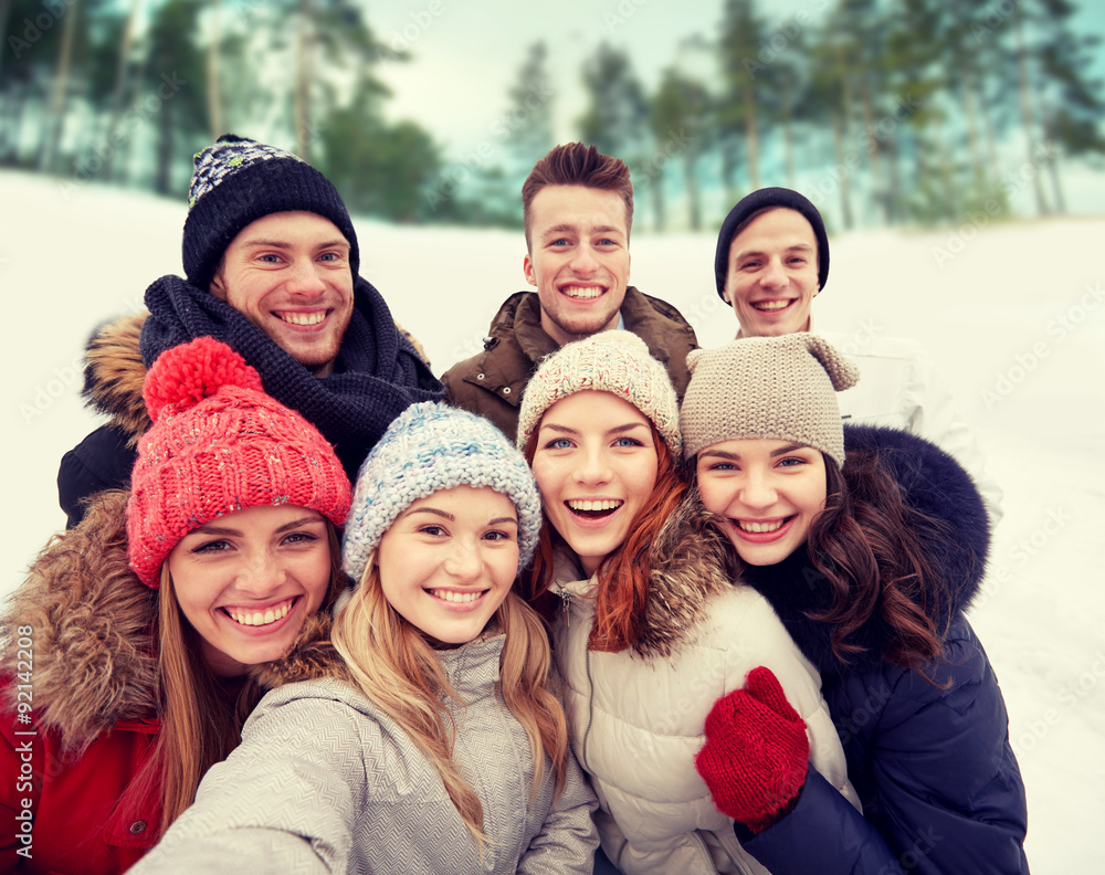 group of smiling friends taking selfie outdoors