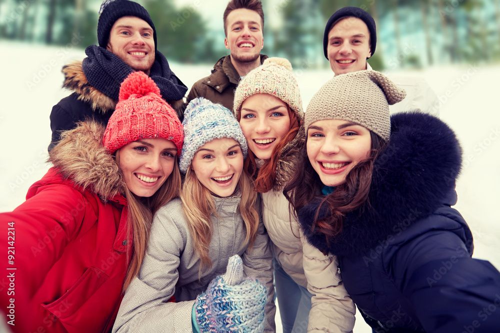 group of smiling friends taking selfie outdoors