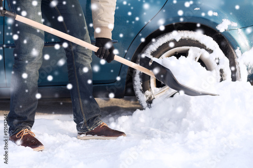 closeup of man digging snow with shovel near car photo