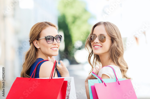 happy young women with shopping bags in city