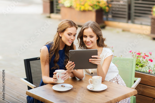 young women with tablet pc and coffee at cafe