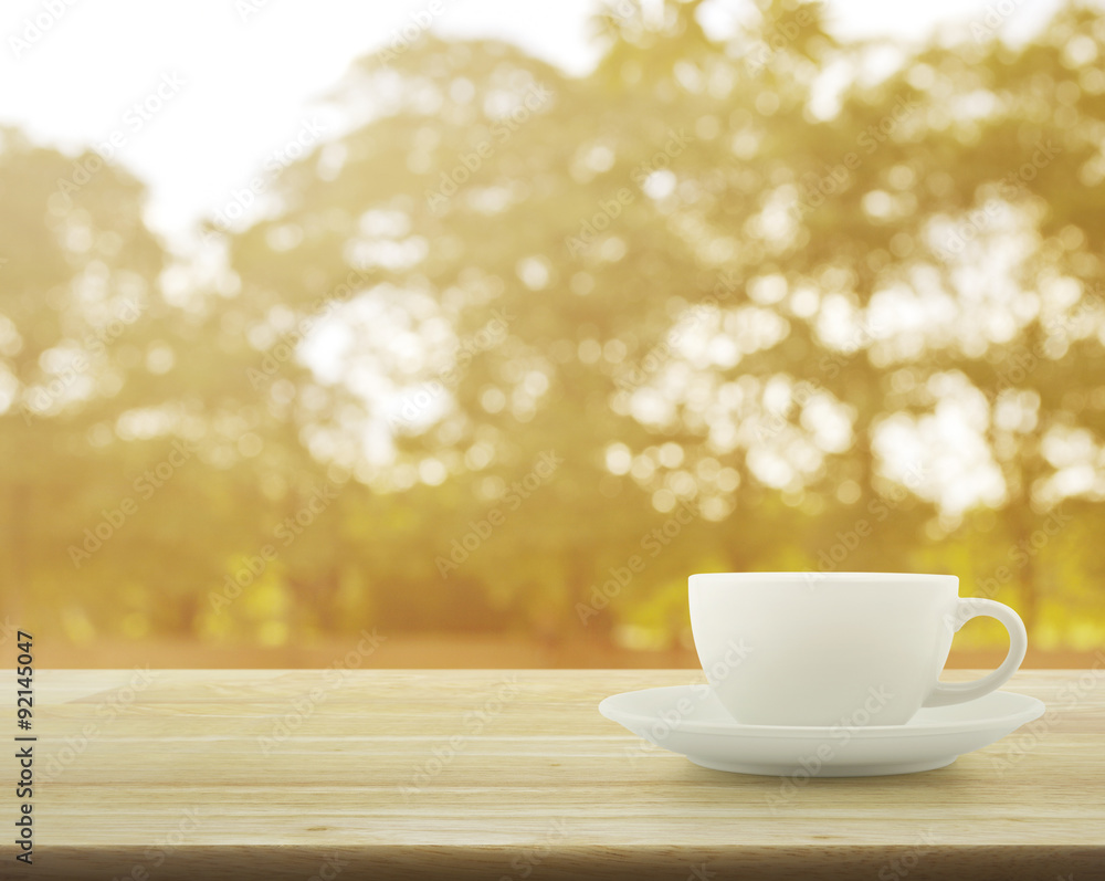 White cup on wooden table over tree bokeh background White cup on wooden table over tree bokeh background