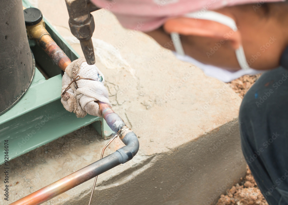 Plumbing contractor works sweating the joints on the copper pipe
