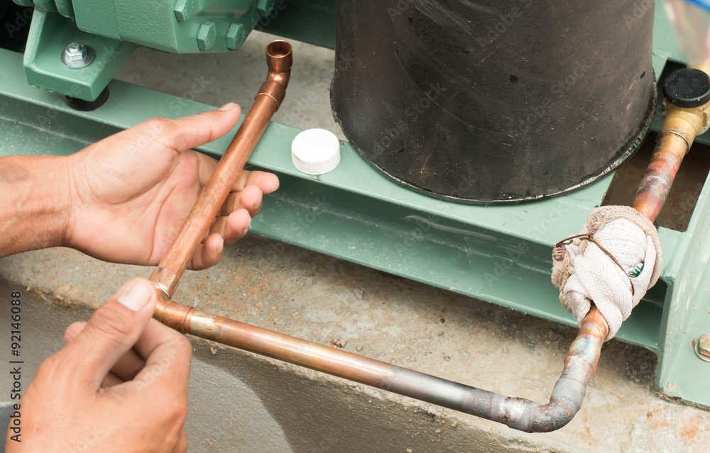 Plumbing contractor works sweating the joints on the copper pipe