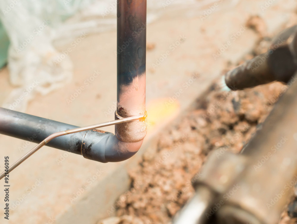 Plumbing contractor works sweating the joints on the copper pipe