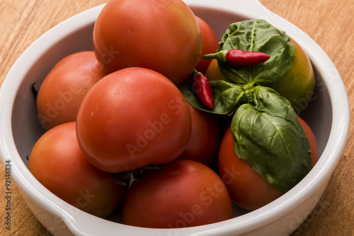 Tomatoes with basil and hot pepper in a white bowl