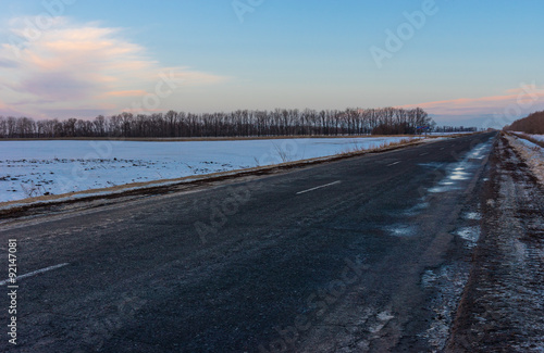 Winter landscape with an empty country road in Ukraine at evening time © Yuri Kravchenko