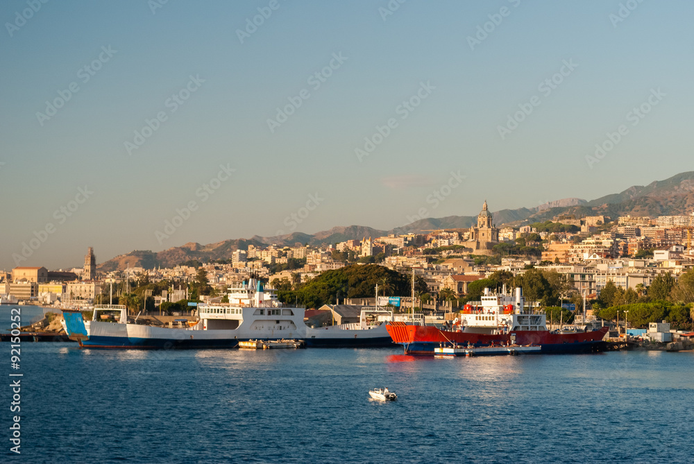 Two boats at the harbor of Messina seen from the sea with city in the background