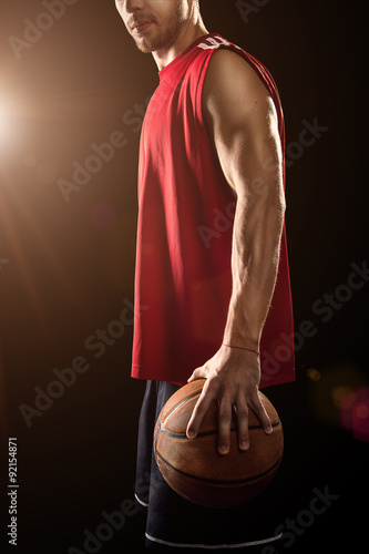 Basketball player holding ball isolated on black background