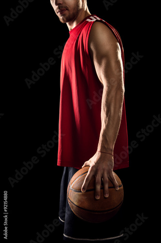 Basketball player holding ball isolated on black background