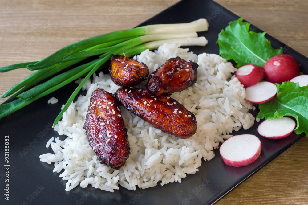 baked chicken wings in soy sauce and rice with herbs Stock Photo