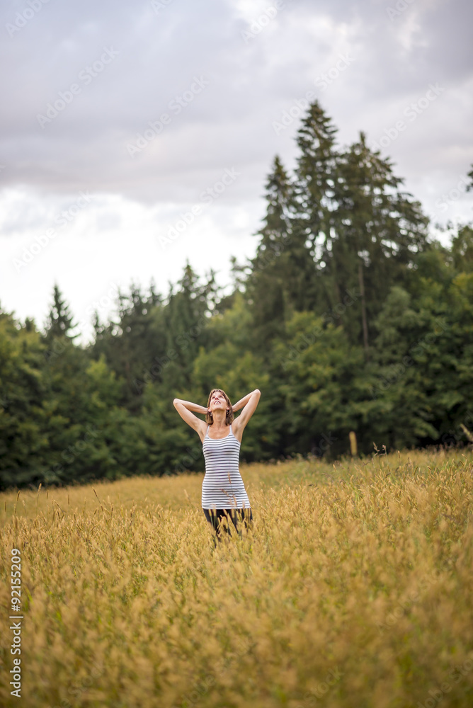 Young woman standing in an autumn field with high grass Young woman standing in an autumn field with high grass