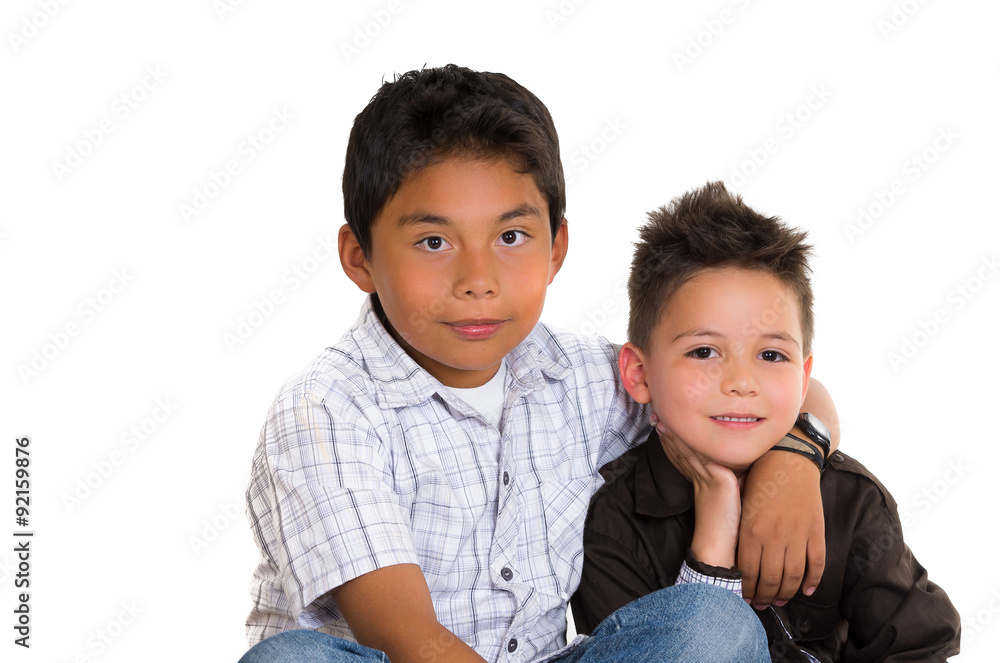 Two small hispanic boys sitting next to each other holding arms Two small hispanic boys sitting next to each other holding arms