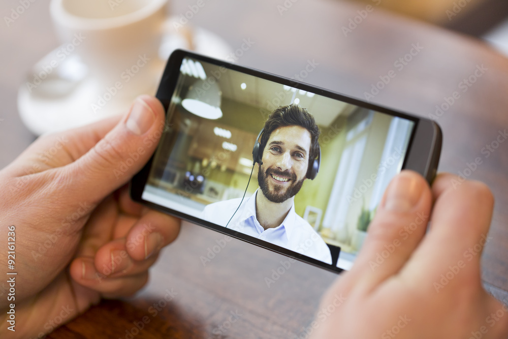 Closeup of a male hand holding a smart phone during a skype video