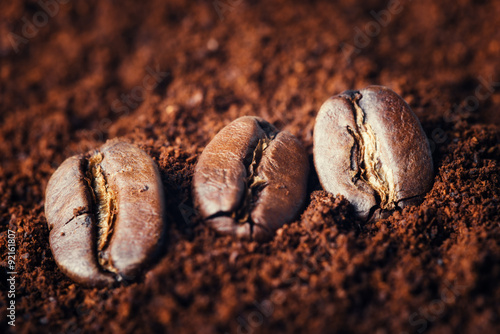 Macrop of coffee beans on ground coffee background