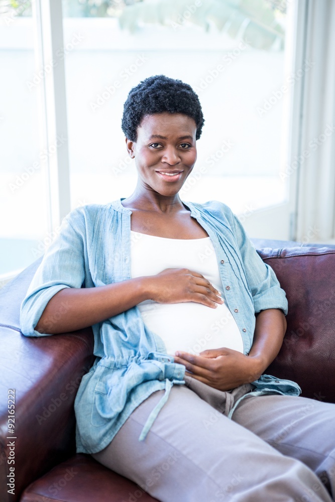 Smiling pregnant woman sitting on the couch Smiling pregnant woman sitting on the couch