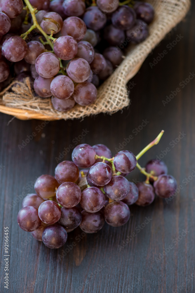 Bunch of grapes in the basket on wooden table Bunch of grapes in the basket on wooden table