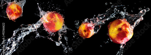 Peaches in water splash on black background, focus on two foregr photo
