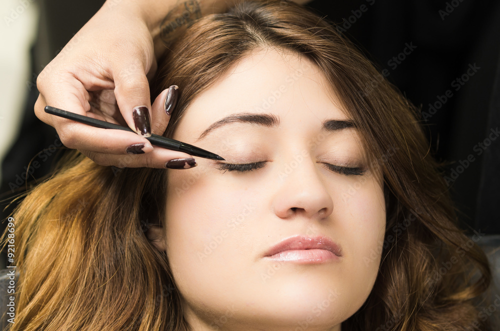 Fototapeta premium Closeup headshot brunette getting makeup treatment by