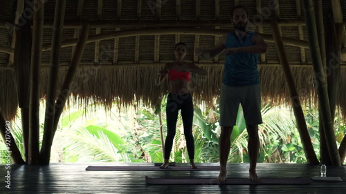 Young couple doing waist twist exercise in wooden barn 
