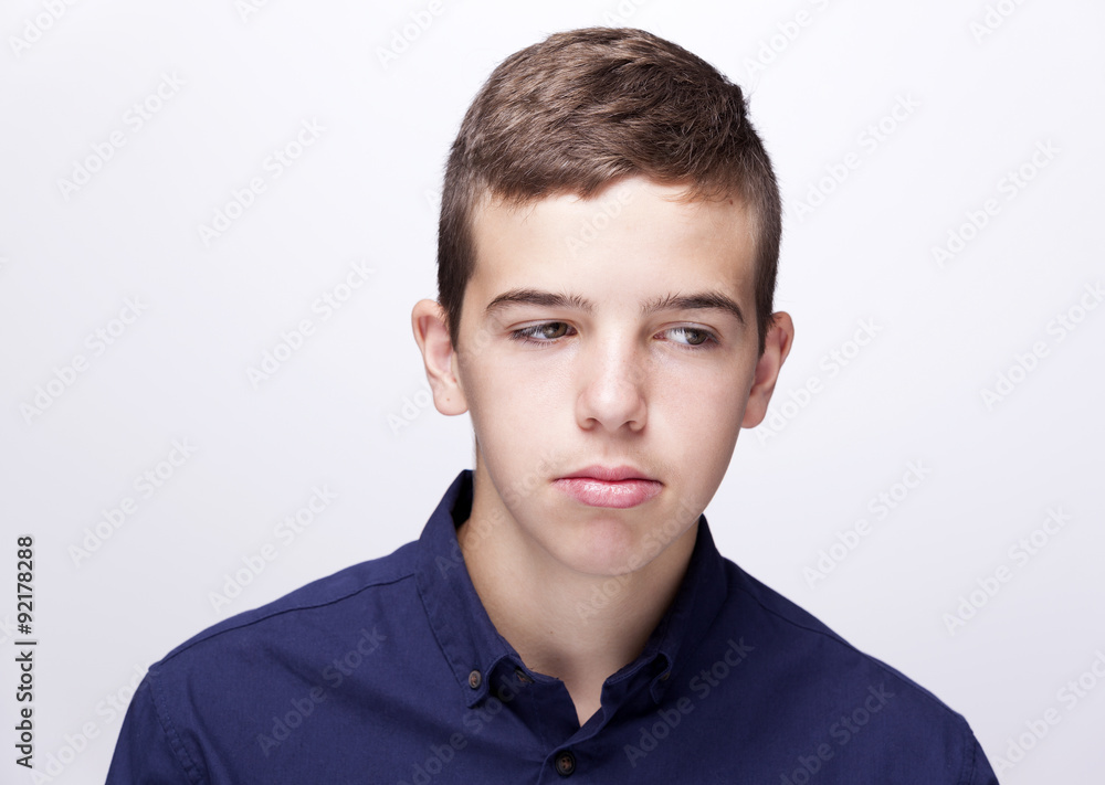 Teen boy looking sad on grey background Teen boy looking sad on grey background
