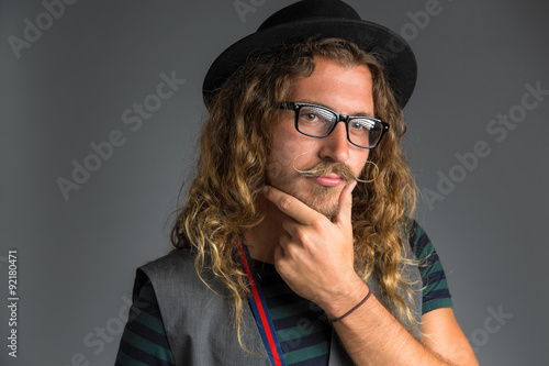 Hipster male rubbing beard in thought handlebar mustache unique looking facial hair style clothing vintage alternative photo