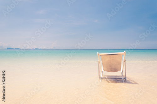 Fototapeta Naklejka Na Ścianę i Meble -  beach chair on beach with blue sky - soft focus with film filter