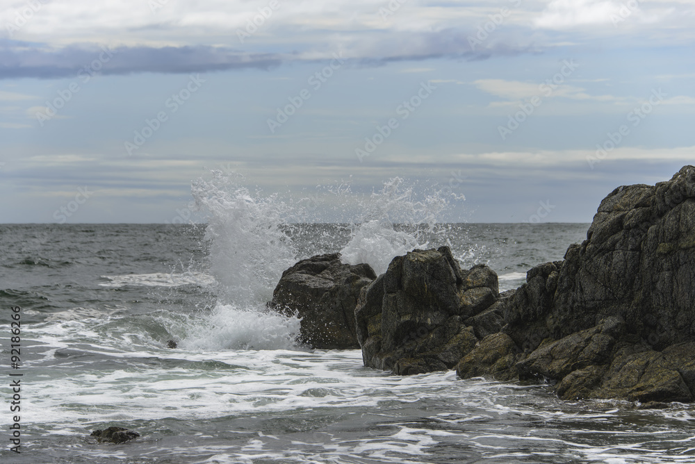 Waves breaking on the rocks .