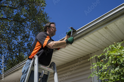 Worker Repairing A Gutter On A Customers Home