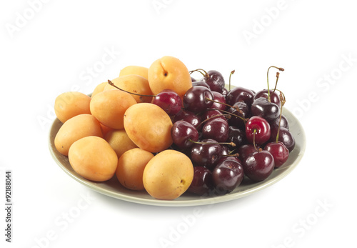 Ripe apricots and cherry on a green ceramic plate isolated on wh