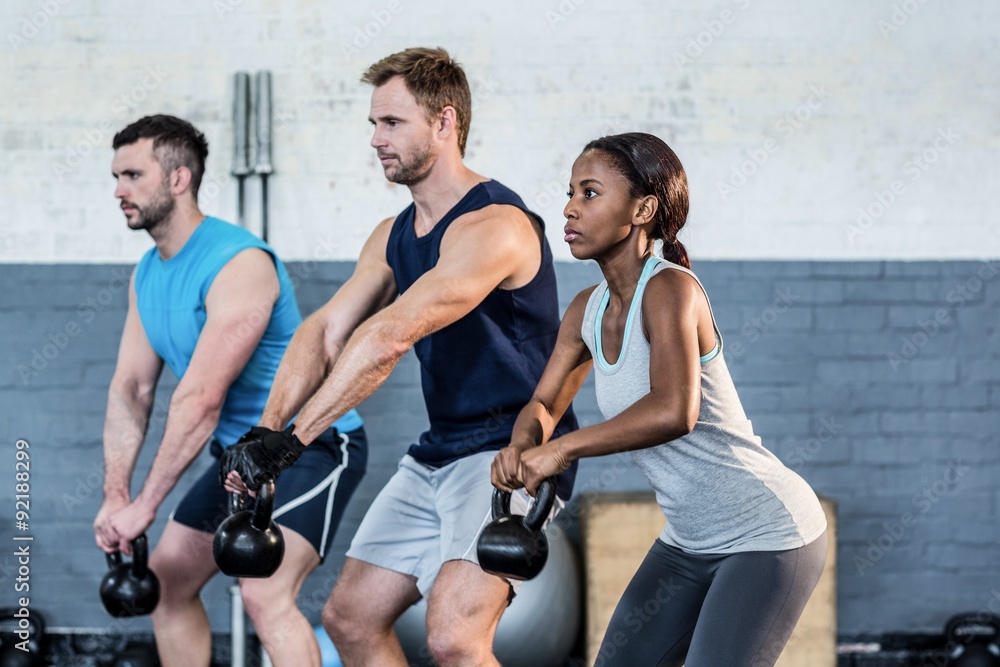 Fit people lifting kettlebells together Fit people lifting kettlebells together