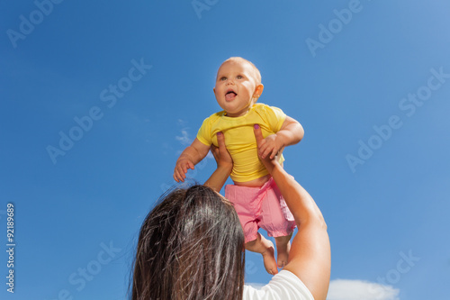 Mother holds her baby up with straight arms