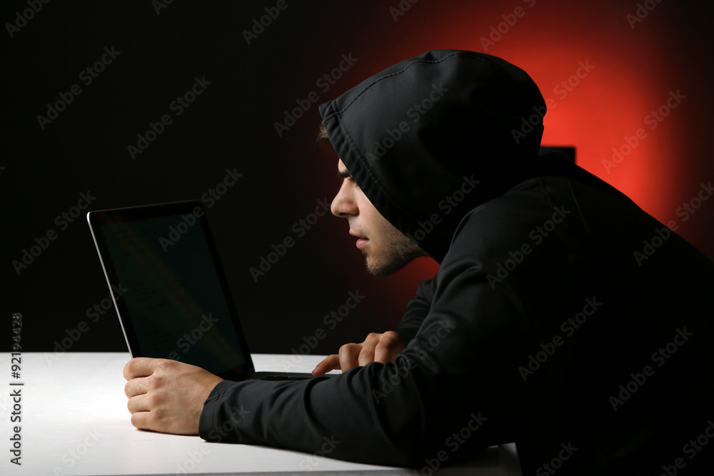 Hacker with computer and laptop on colorful dark background Hacker with computer and laptop on colorful dark background
