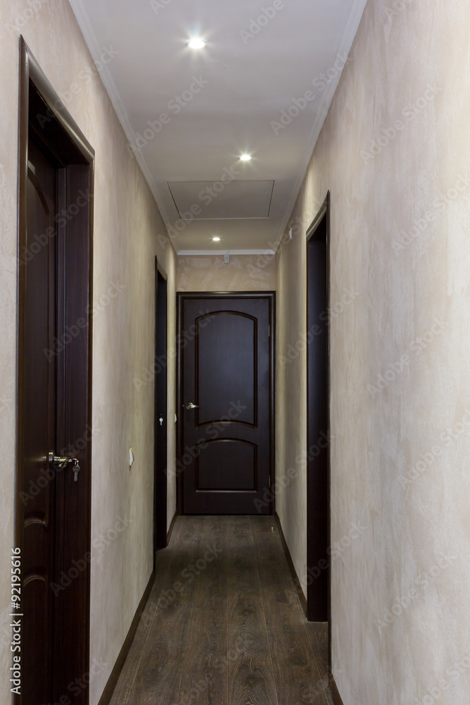 narrow corridor with four brown doors narrow corridor with four brown doors