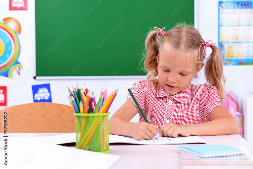 Little girl drawing at the desk in classroom Little girl drawing at the desk in classroom