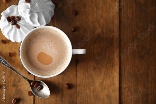 Cup of coffee with zephyr and beans on wooden table, top view