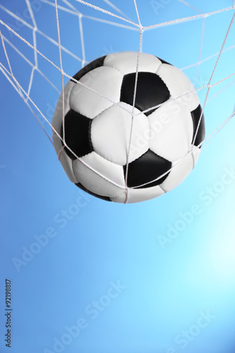 Soccer ball in the net on blue background © Africa Studio