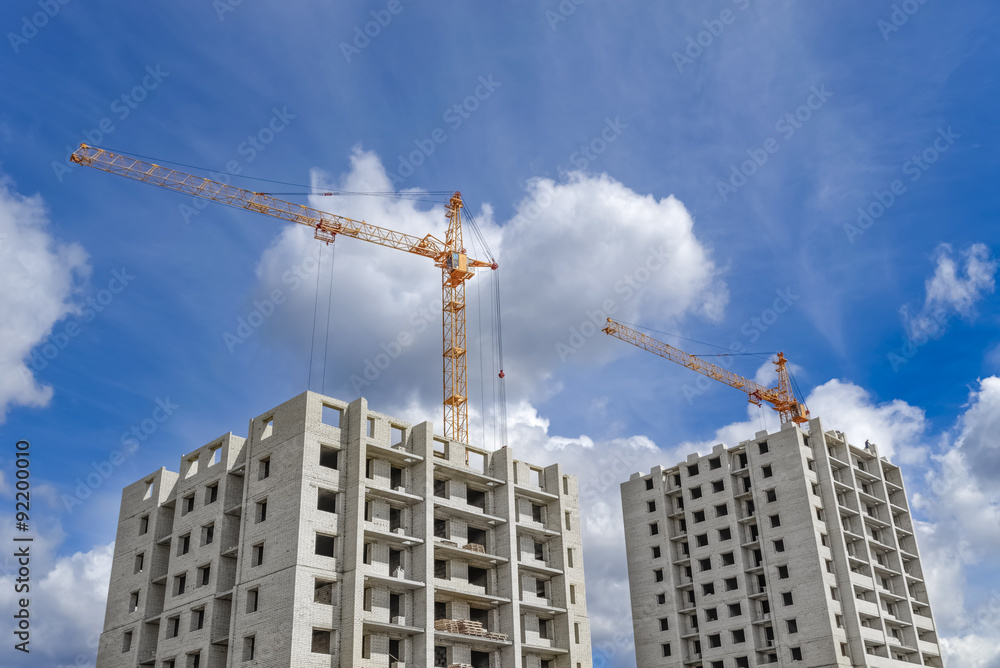 Multi-storey houses under construction and high-rise crane Multi-storey houses under construction and high-rise crane