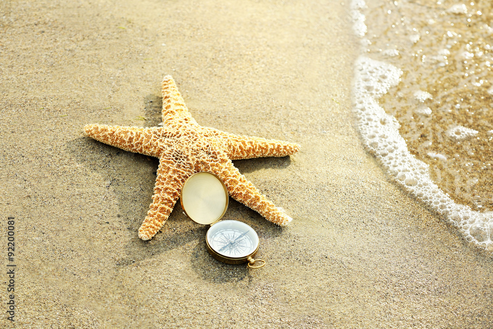 Compass with sea star on sand beach background Compass with sea star on sand beach background