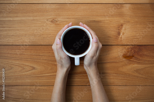 woman hands holding mug of hot drink that standing on wooden tab