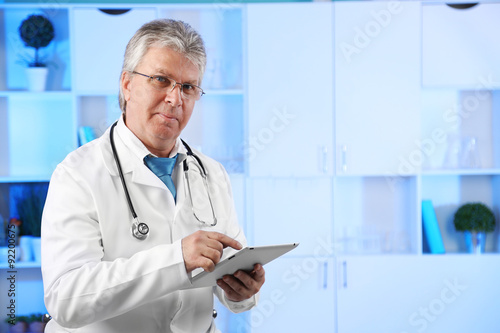 Doctor with digital tablet at his workplace
