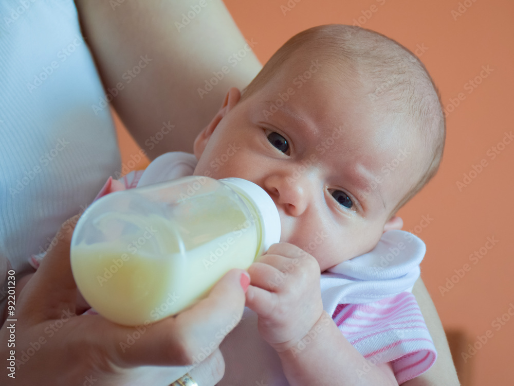 the Month-old cute baby girl bottle-fed by the mother.