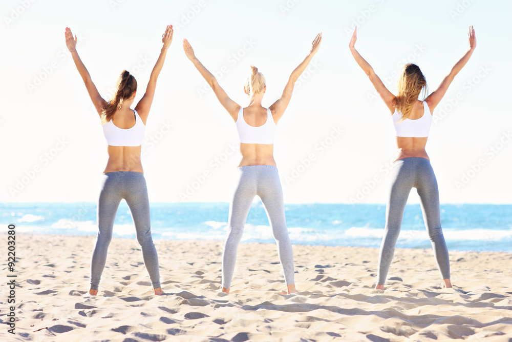 Group of women practising yoga on the beach Group of women practising yoga on the beach