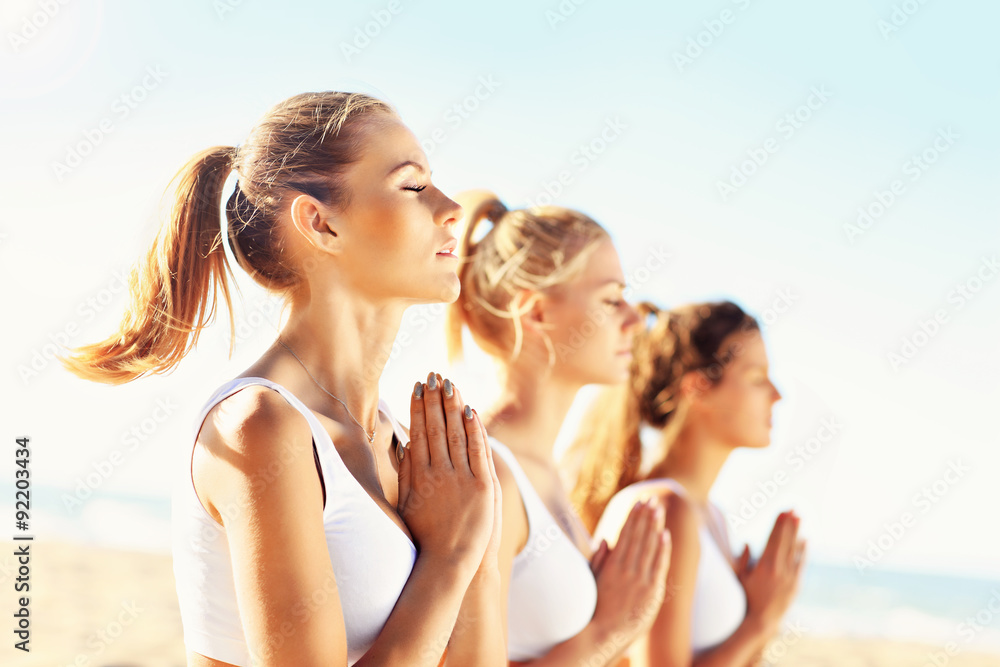 Group of women practising yoga on the beach Group of women practising yoga on the beach
